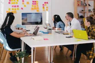 a marketing team sitting on chairs looking towards lcd and seeing the stats of social media and seo